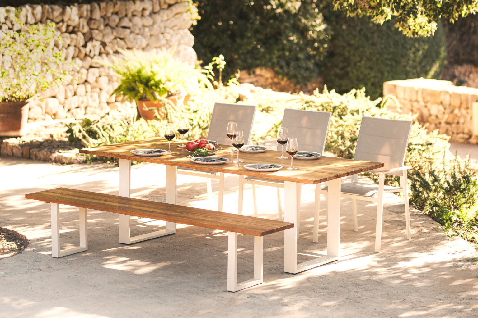 Gartenbank und Tisch mit Stühlen im Sonnenschein